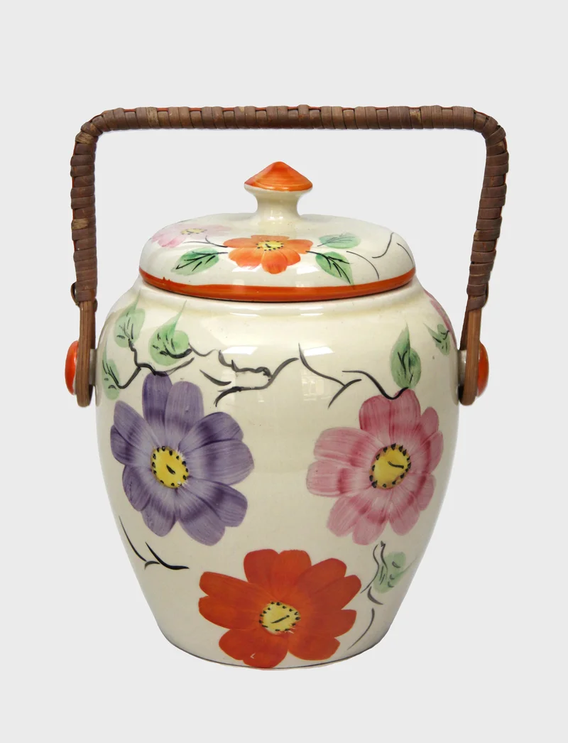 Art déco koekjestrommel - Porselein › Serviesgoed - €35.00 - Porselein pot met rieten handvat.
18cm hoog, 13cm diameter
Gemerkt: Arthur Wood, Longport
1934-1945