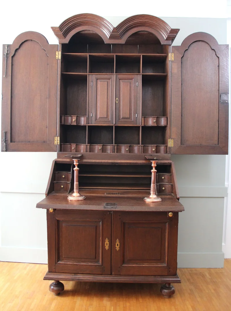 Double dome bureau 18e eeuw - Meubel › Kasten - €1495.00 - Tweeledige eiken bureau met gesloten opbouw. Opgedeeld in vele vakken en met twee uitschuifbare kandelaarhouders tussen onder- en bovendeel.
De "duble dome" verwijst naar het dubbele pediment bovenaan.

94cm breed, 59cm diep aan het bureaugedeelte, 215cm hoog.

Georgean periode, 18e eeuw