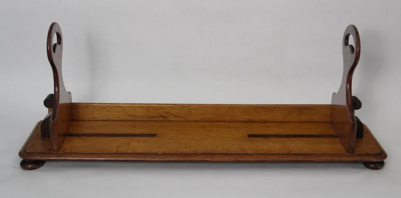 Draagbare boekenstand - Diversen › Varia - €295.00 - Draagbare boekenstand die oorspronkelijk gebruikt werd in leeszalen van bibliotheken. Met deze boekenstand kon men een serie boeken ophalen en naar de leestafel dragen. De twee steunen zijn verschuifbaar om de boeken samen te houden. De steunrand achteraan belet dat de boeken uit de drager schuiven.
Gemaakt in eik.
70cm lang, 20cm diep, steunen 28cm hoog.
Victoriaanse periode, late 19e eeuw.