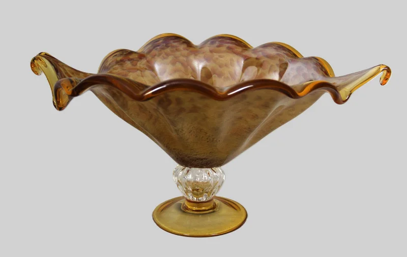 Glazen schaal - Glas › Schalen - €95.00 - Schaal op voet in geelkleurig gemarmerd glas.
42 x 33 cm, 20cm hoog
Ca 1940-1960