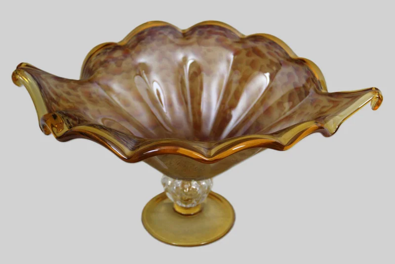 Glazen schaal - Glas › Schalen - €95.00 - Schaal op voet in geelkleurig gemarmerd glas.
42 x 33 cm, 20cm hoog
Ca 1940-1960