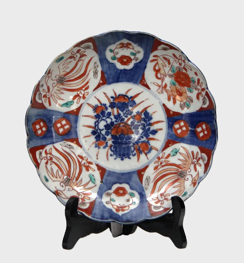 Imari bord (11) - Porselein › Borden - €30.00 - Bord met gelobde rand, rood-blauw decor met centraal bloemenmand en blauwe decoratie op achterrand.
21cm diameter
19e eeuw