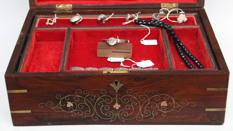 Mahonie juwelenkist - Diversen › Dozen en kistjes - €160.00 - Een grote mahoniehouten kist met gebogen deksel en met intarsia van koper bladmotieven en filets. Versterkt op de hoeken met messing hoekprofielen.
Binnenin ingericht voor juwelen.
40 x 28cm, 19cm hoog.
Edwardian periode; ca 1910/1930