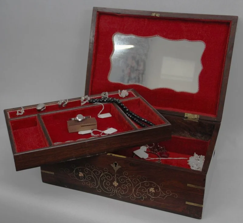 Mahonie juwelenkist - Diversen › Dozen en kistjes - €160.00 - Een grote mahoniehouten kist met gebogen deksel en met intarsia van koper bladmotieven en filets. Versterkt op de hoeken met messing hoekprofielen.
Binnenin ingericht voor juwelen.
40 x 28cm, 19cm hoog.
Edwardian periode; ca 1910/1930