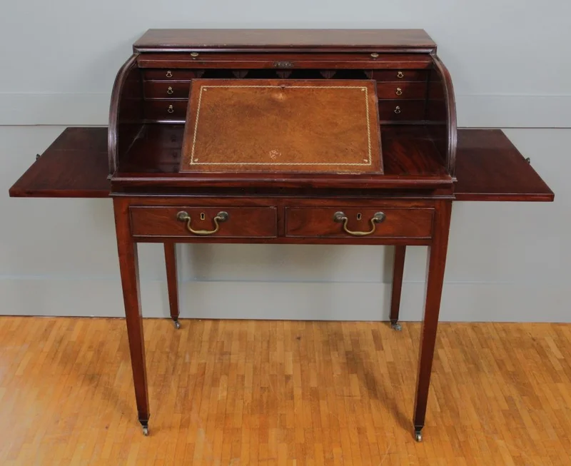 Rolluikbureautje - Meubel › Bijzetmeubels - Mahoniehouten rolluikbureautje met uitschuifbaar en opklapbaar schrijfblad, diverse binnenladen en pigeonholes. Twee uitschuifbare legplankjes aan de zijkanten. Originele castors.
76 x 57cm; 96cm hoog.
Georgean stijl; Edwardian periode; ca 1930
