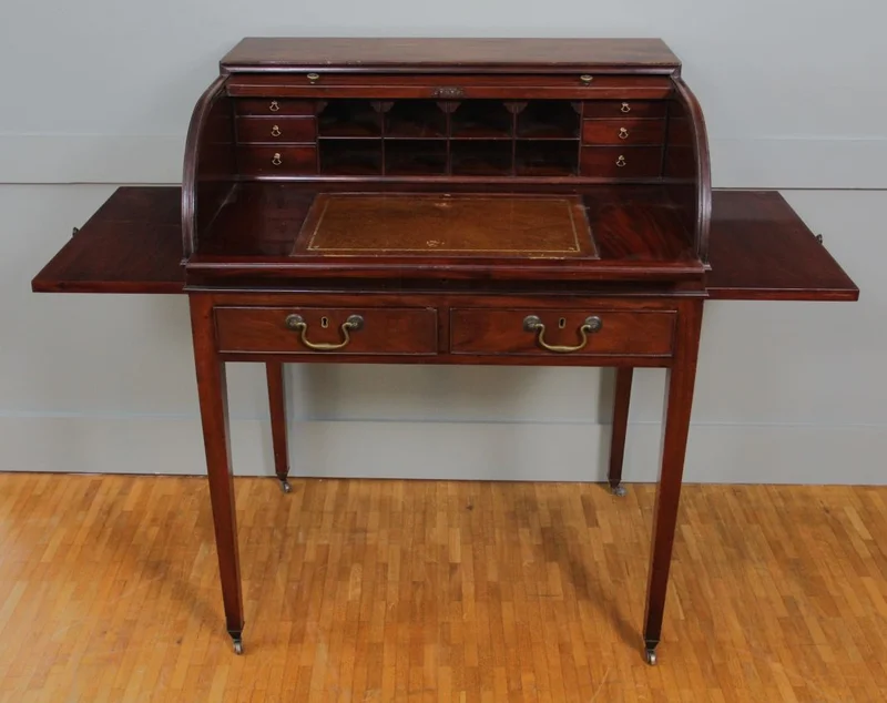 Rolluikbureautje - Meubel › Bijzetmeubels - Mahoniehouten rolluikbureautje met uitschuifbaar en opklapbaar schrijfblad, diverse binnenladen en pigeonholes. Twee uitschuifbare legplankjes aan de zijkanten. Originele castors.
76 x 57cm; 96cm hoog.
Georgean stijl; Edwardian periode; ca 1930