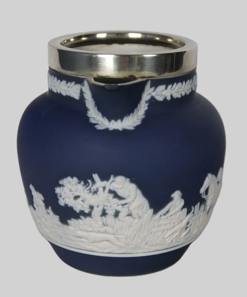 Roomkan met Wedgewood motief (2) - Porselein › Serviesgoed - €20.00 - Roomkan met decoratie in de stijl van Wedgewood en een verzilverde kraag.
Kleine schilfer van de schenktuit.
Gemerkt: Tunstall England, Adam
12cm hoog
19e eeuw