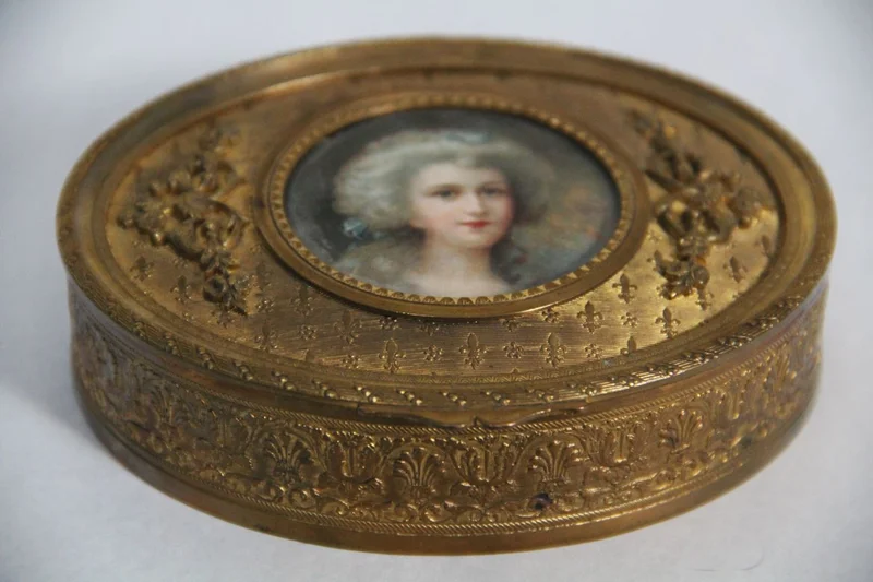 Vergulde doos - Diversen › Dozen en kistjes - €40.00 - Een kleine ovale metalen doos, verguld aan de buitenzijde, met een centraal rond glas om een foto achter te plaatsen.
11 x 9cm ovaal, 3cm hoog
Napoleon III periode; 1850/1870